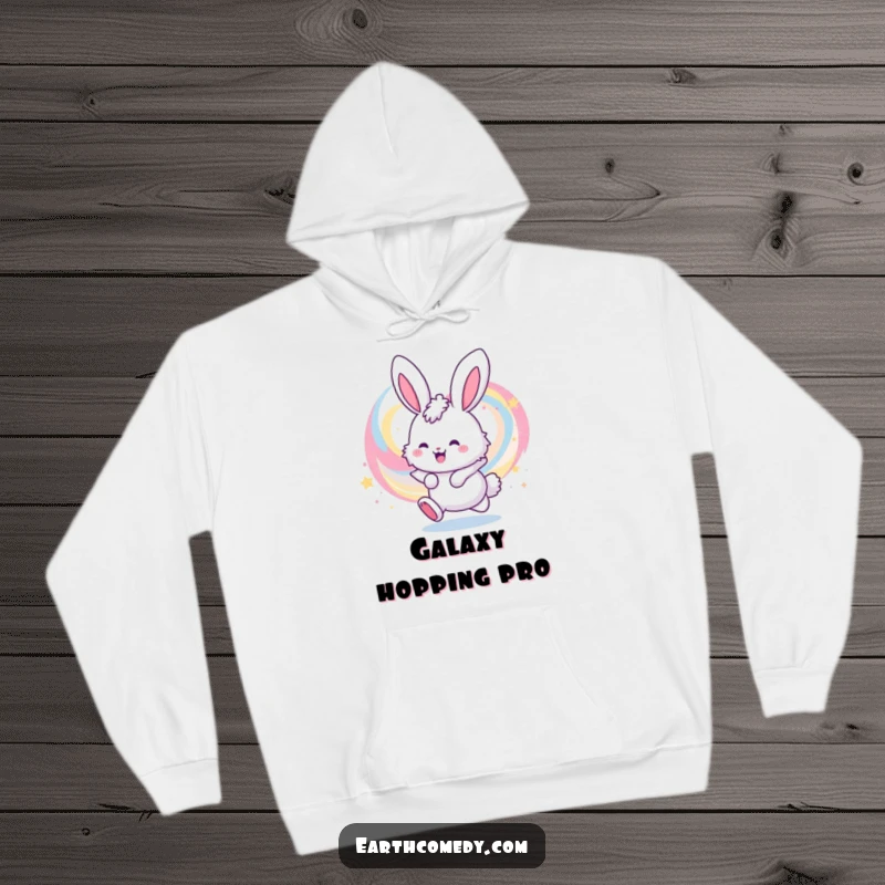 Funny hoodie with a cute, fluffy bunny character energetically bouncing near a mesmerizing, colorful galaxy, radiating fun and warmth.